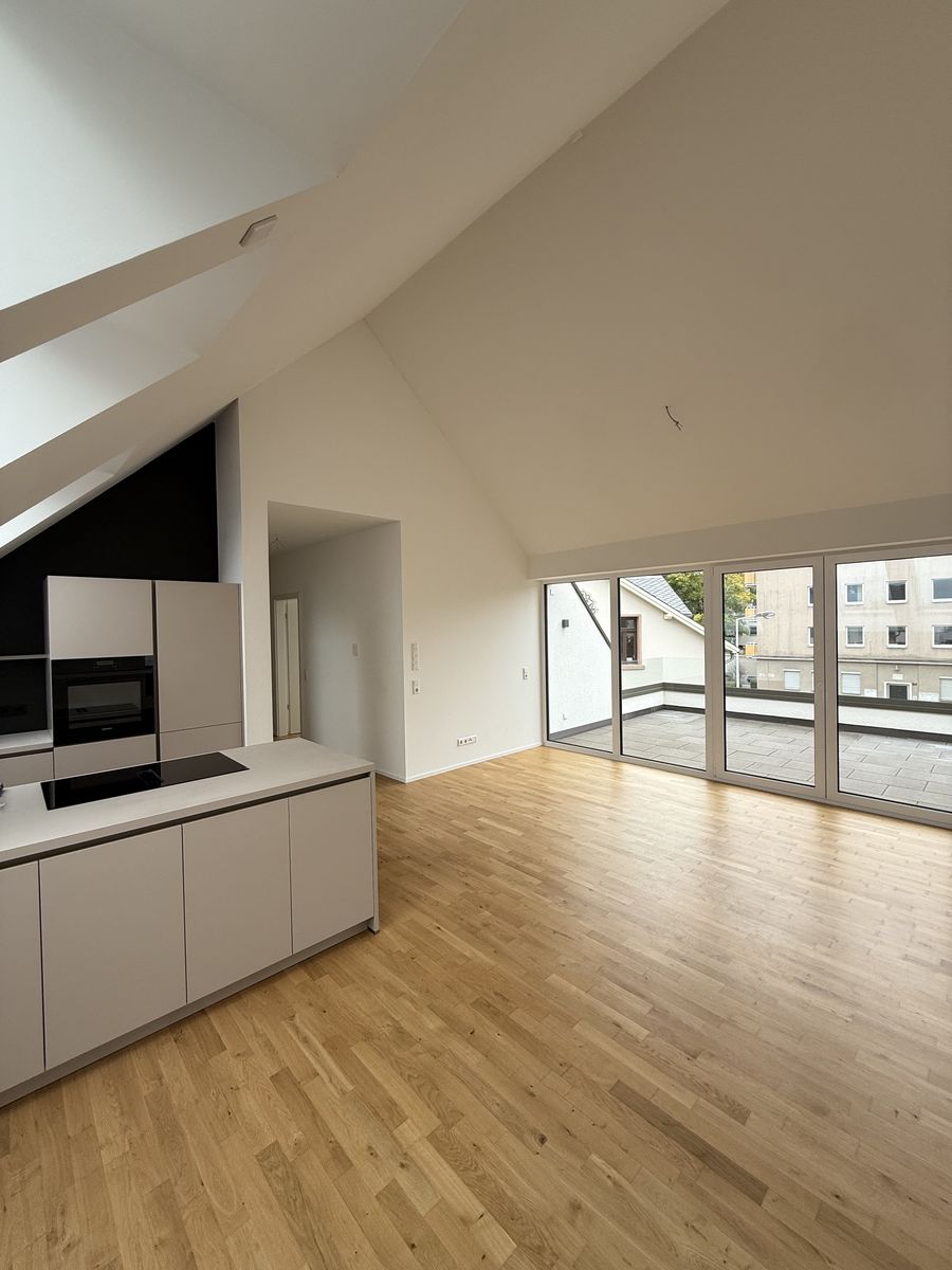 Offener Wohn- und Essbereich unter dem Dach mit Kücheninsel, Eichenparkett und großer Fensterfront zur Dachterrasse